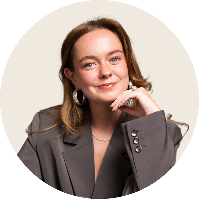 Een vrouw in pak en oorbellen staat lachend in een kring.