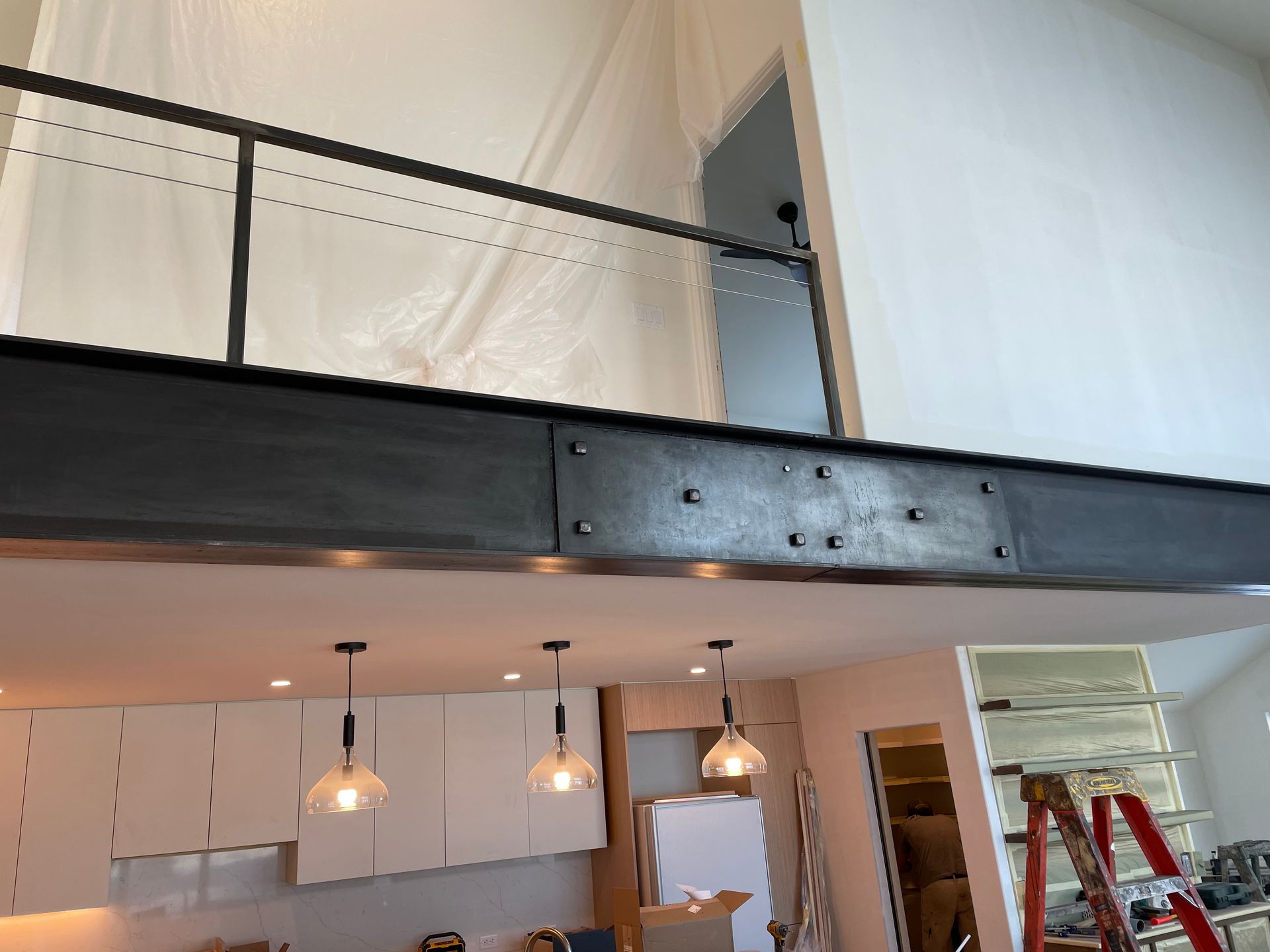 A kitchen with a balcony and a ladder in the background.