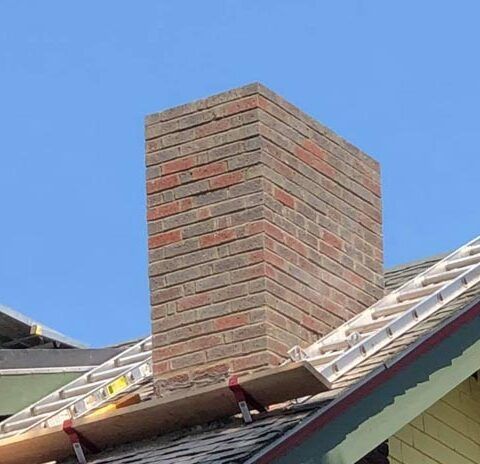 Brick chimney on a rooftop against a blue sky