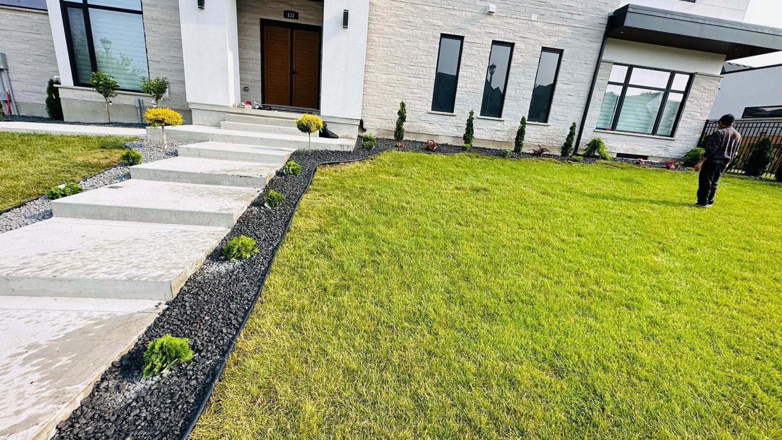 Modern house exterior with stone walkway, manicured lawn, and dark mulch edging