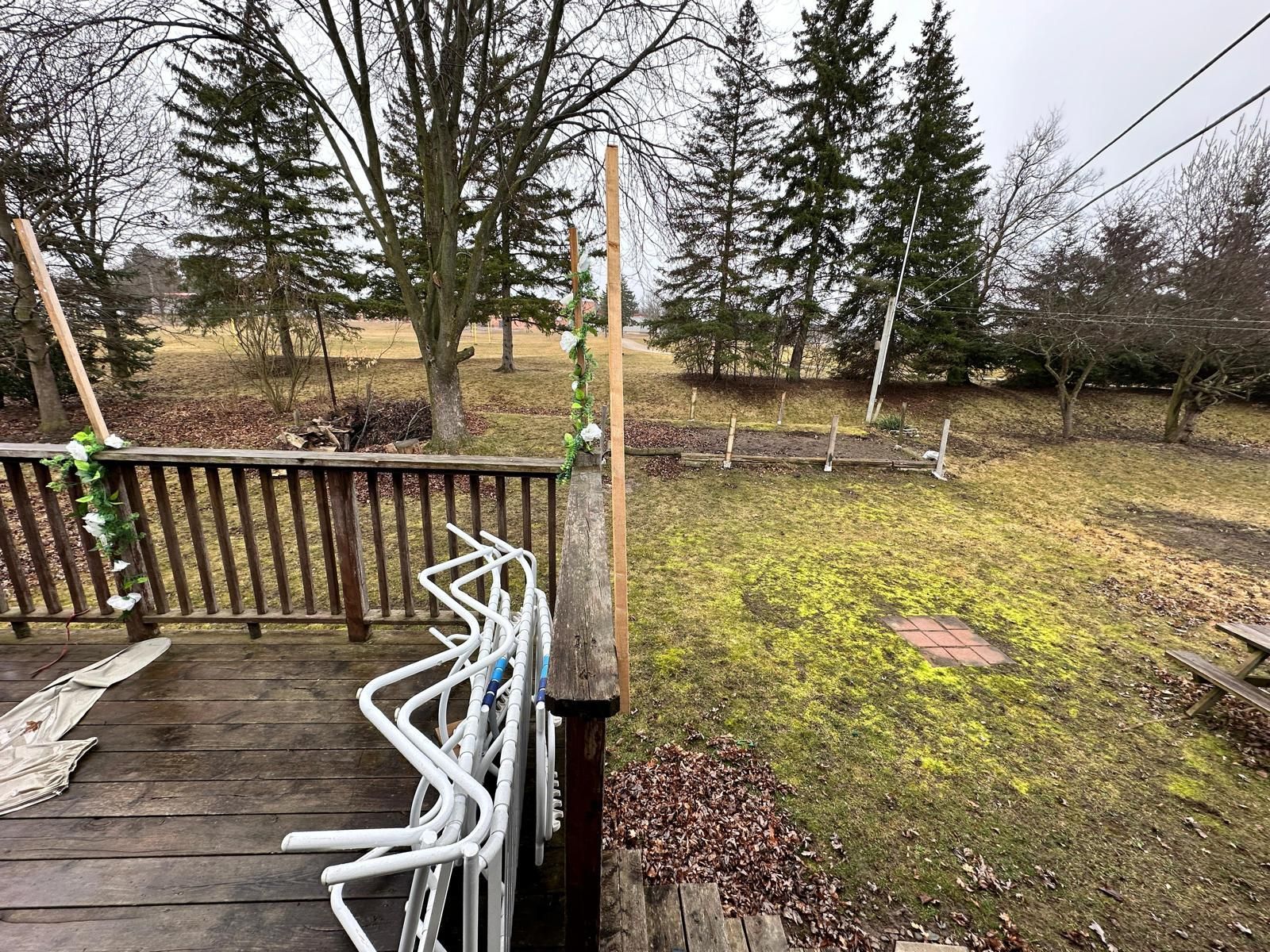 A deck with a bunch of chairs on it and trees in the background.