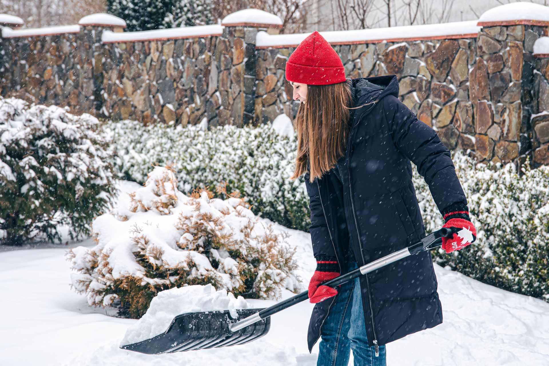A woman is shoveling snow in a yard.