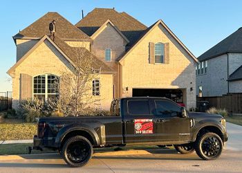 A black truck is parked in front of a large house.