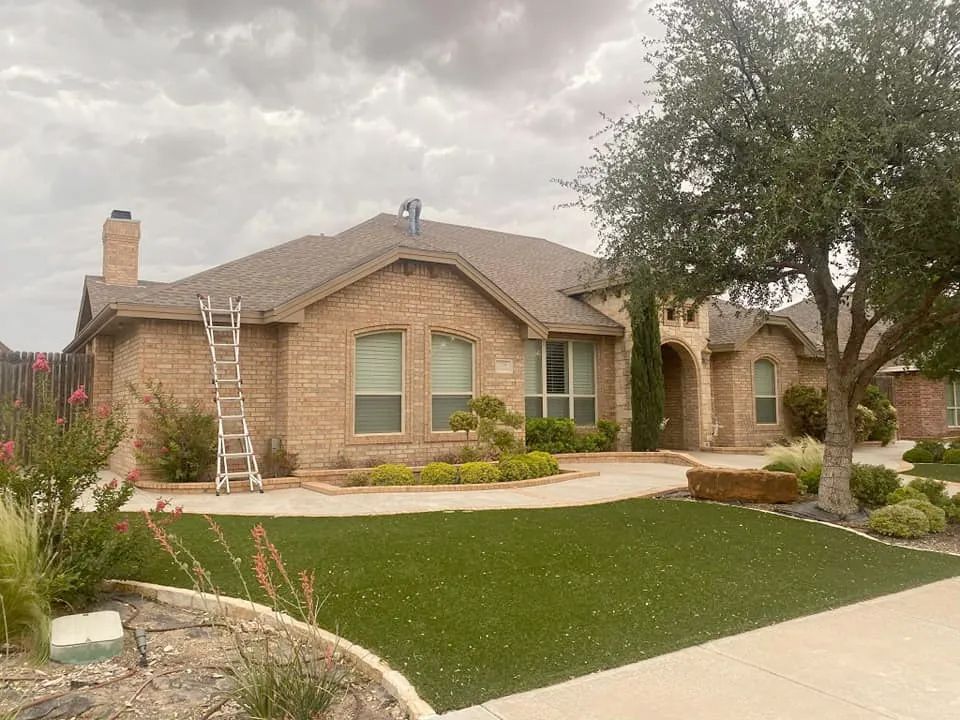 A large brick house with a ladder on the roof.