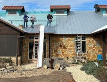 A group of people are working on the roof of a house.