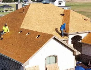 Two men are working on the roof of a house