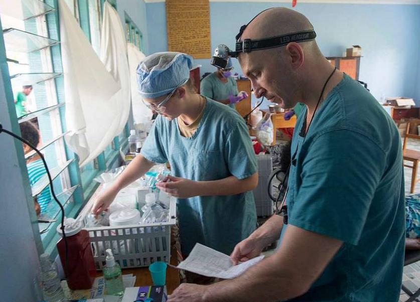 A man and a woman in scrubs are working in a room.