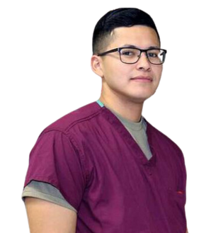 A man wearing glasses and a purple scrub top is standing in front of a white background.