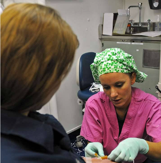 A woman in a pink scrub is talking to another woman