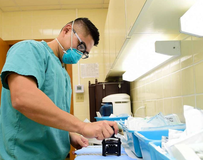 A man wearing a mask and goggles is working in a hospital room
