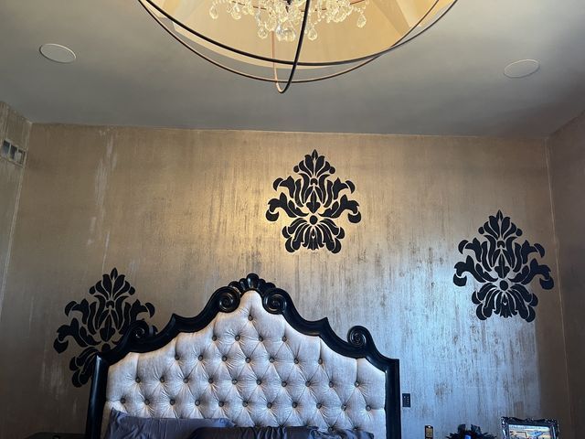 Bedroom with black and cream headboard, black damask wall decals on textured gold wall.