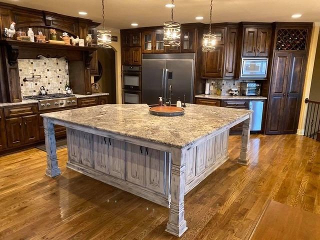Kitchen with light granite island, dark wood cabinets, stainless steel appliances, and hardwood floors.