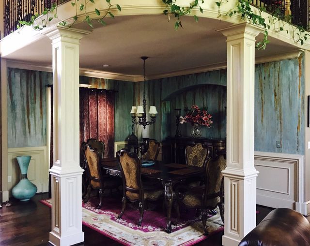 Elegant dining room with ornately carved furniture, blue-green walls, and ornate ceiling details.