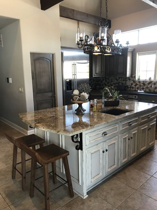 Kitchen with granite countertop island, dark wood cabinets, and bar stools.
