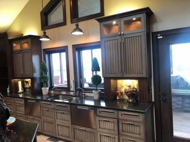 Kitchen with dark cabinets, black countertops, stainless steel sink, and windows.