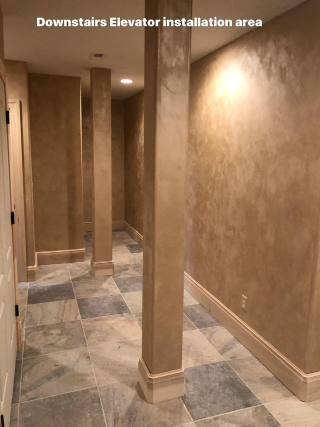 Hallway with textured beige walls, columns, and tiled floor, labeled 