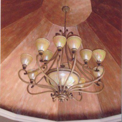 Chandelier with multiple lights suspended from a reddish-brown, domed ceiling.