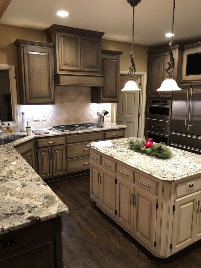 Kitchen with dark wood cabinets, granite countertops, island, and stainless steel appliances.
