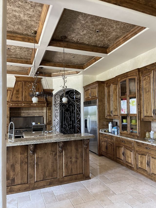 Kitchen with wooden cabinets, island, and ceiling beams; stainless steel appliances.