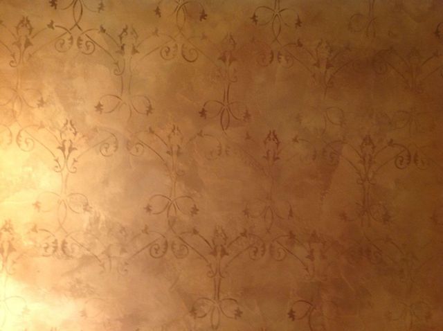 Brown wall with faded, repeating floral pattern.
