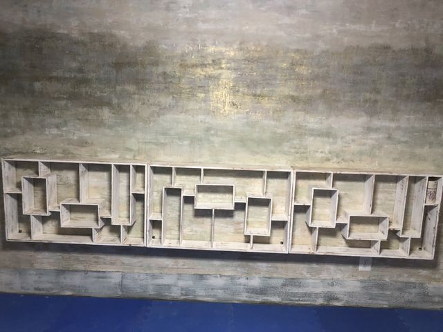 Decorative rectangular concrete panel with geometric cutouts, mounted on a textured wall.