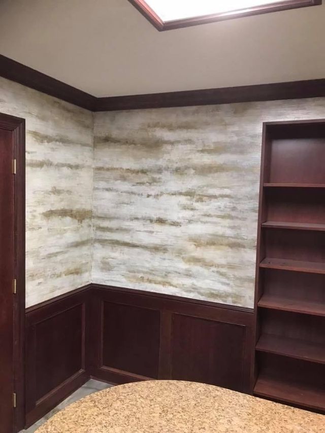 Office interior with textured walls, dark wood trim, built-in shelving, and a wood door.