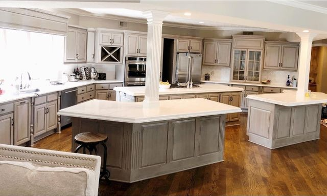 Spacious kitchen with gray cabinets, multiple islands, white countertops, and wood flooring.