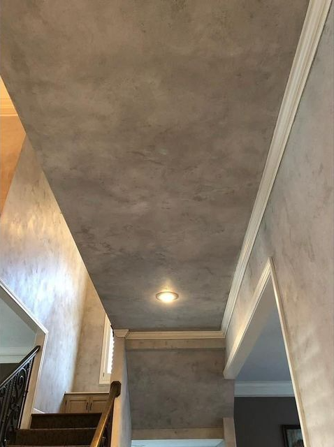 Gray textured ceiling and wall with white trim and a recessed light in a hallway.