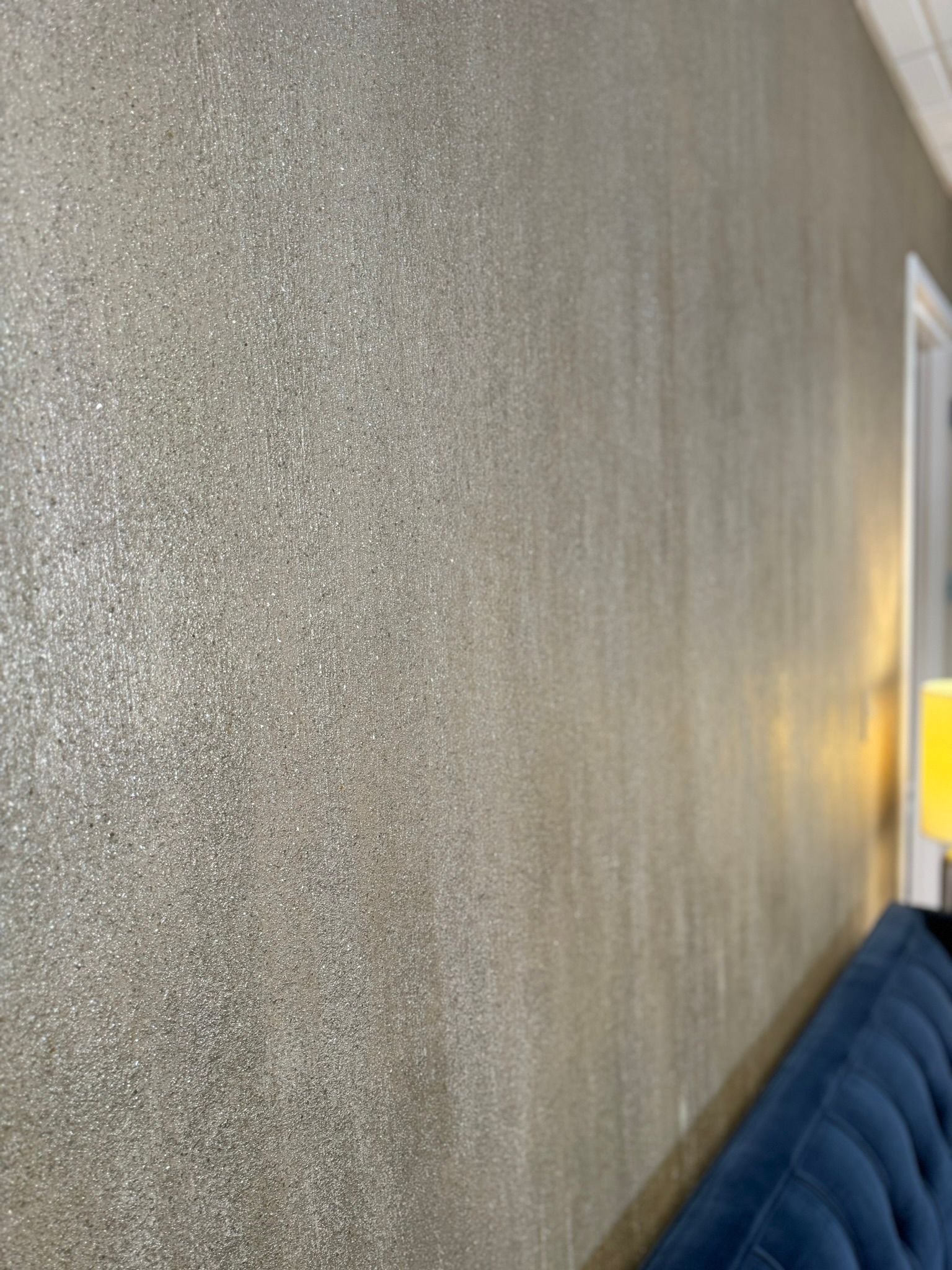Textured gray wall beside a blue sofa in a softly lit room