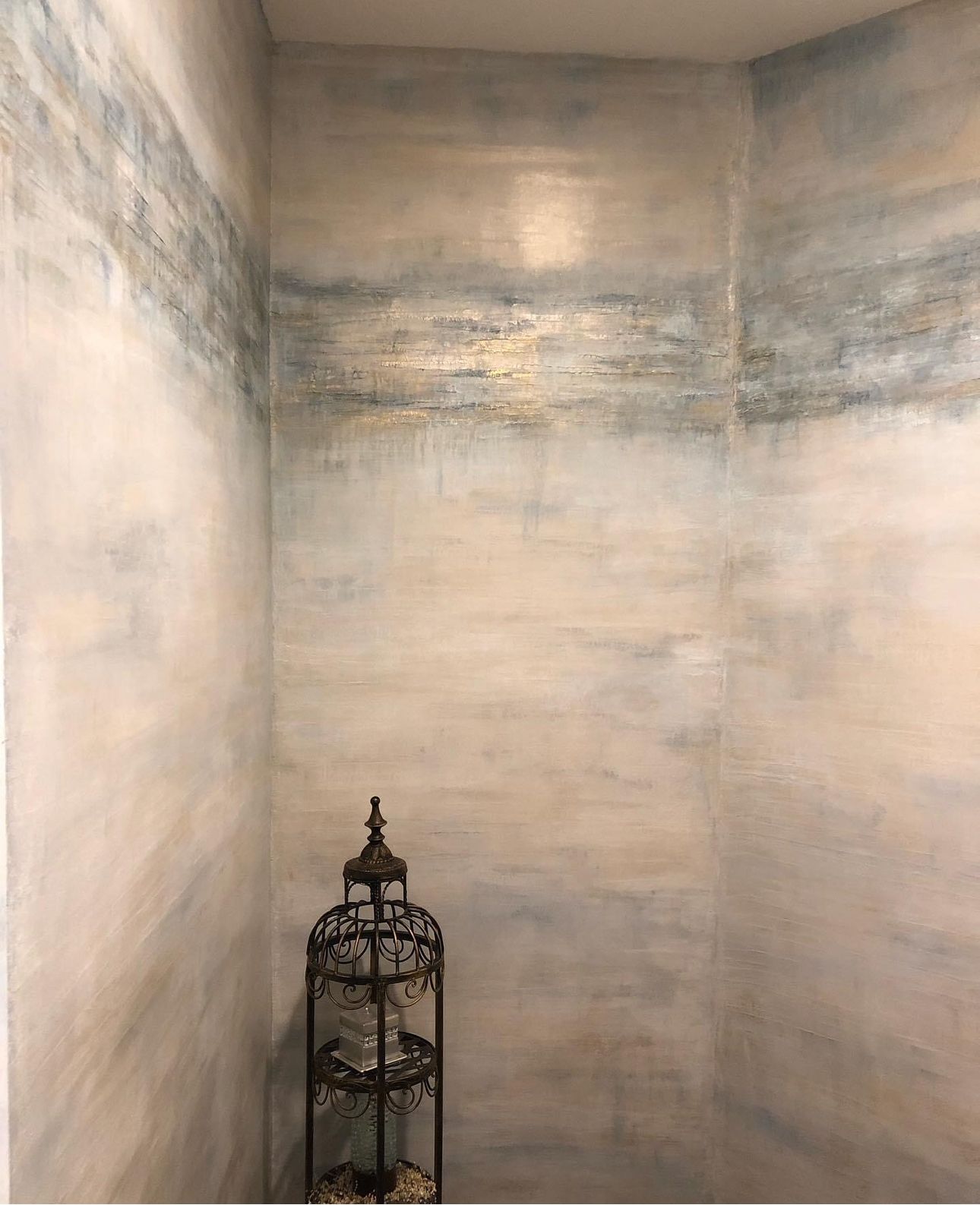 Bare corner with pale textured walls and a decorative black birdcage on the floor.