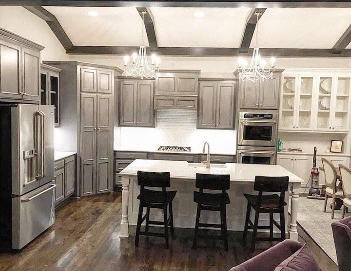 Gray and white kitchen with island, stainless steel appliances, and dark wooden floors.