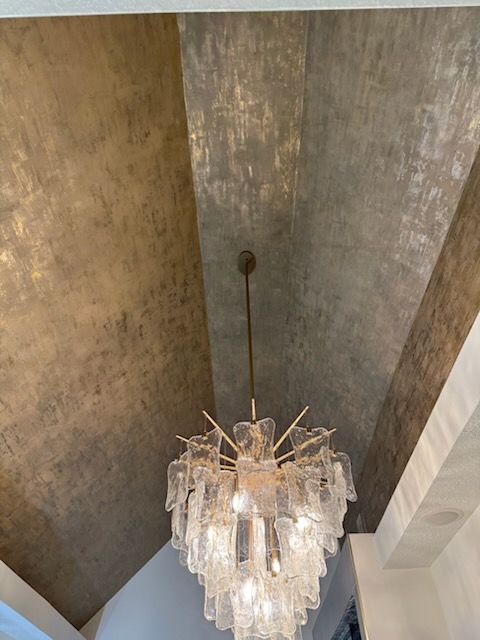 Crystal chandelier hanging from a vaulted textured ceiling in a warm-toned room