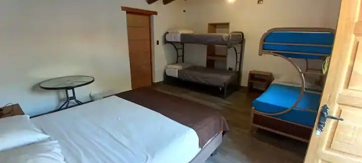Un dormitorio con una cama, literas y una mesa.