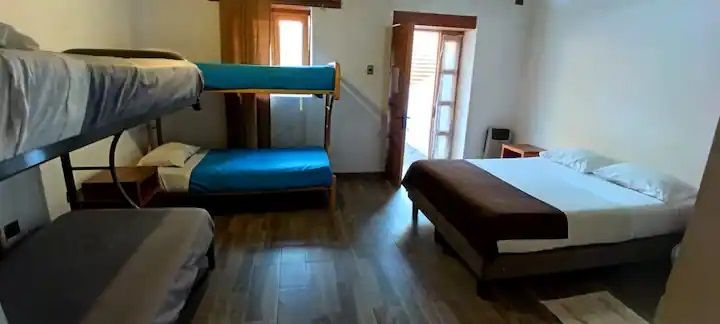 Una habitación de hotel con una litera, una cama y un sofá.