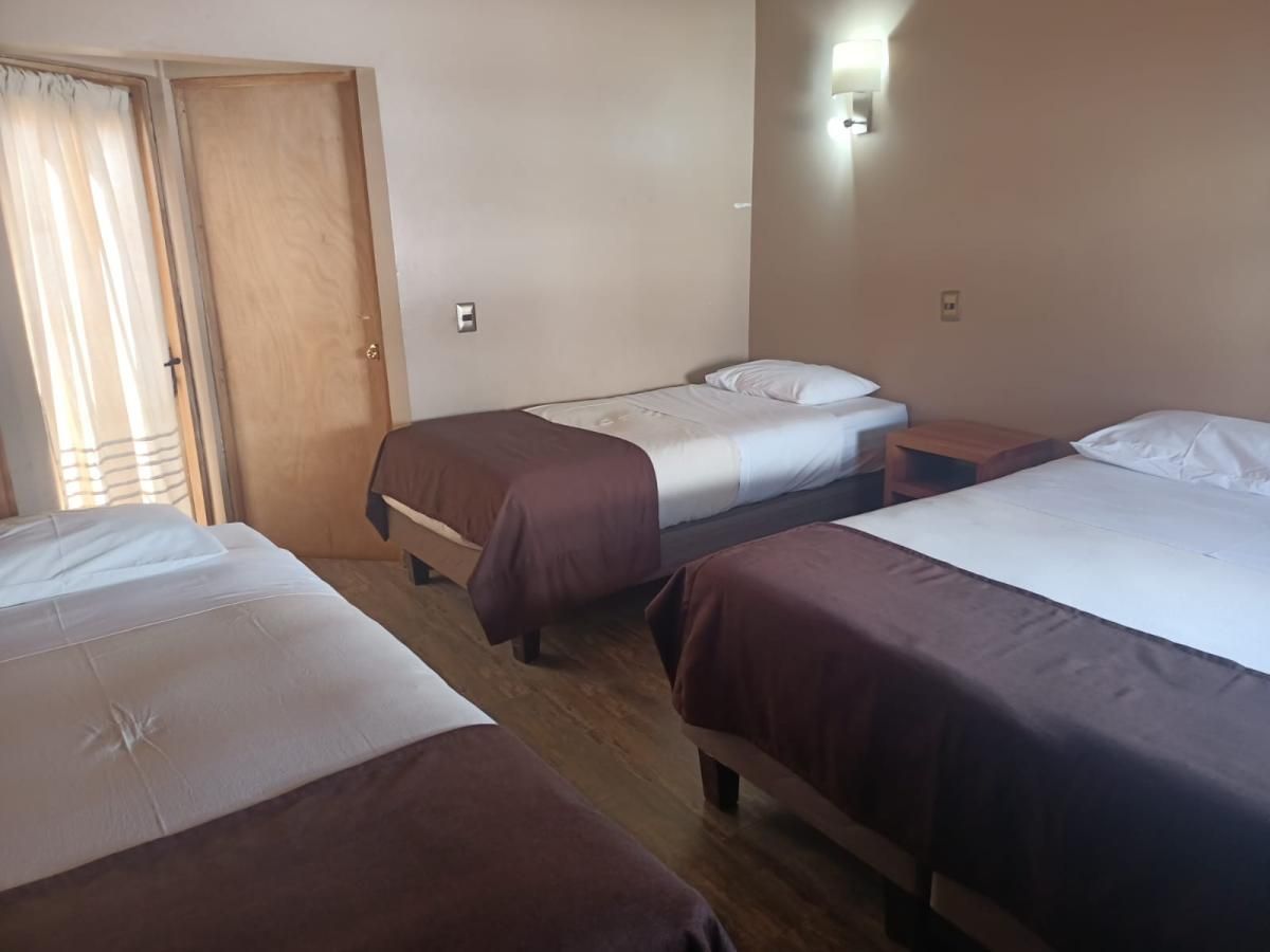 Una habitación de hotel con tres camas y una puerta.