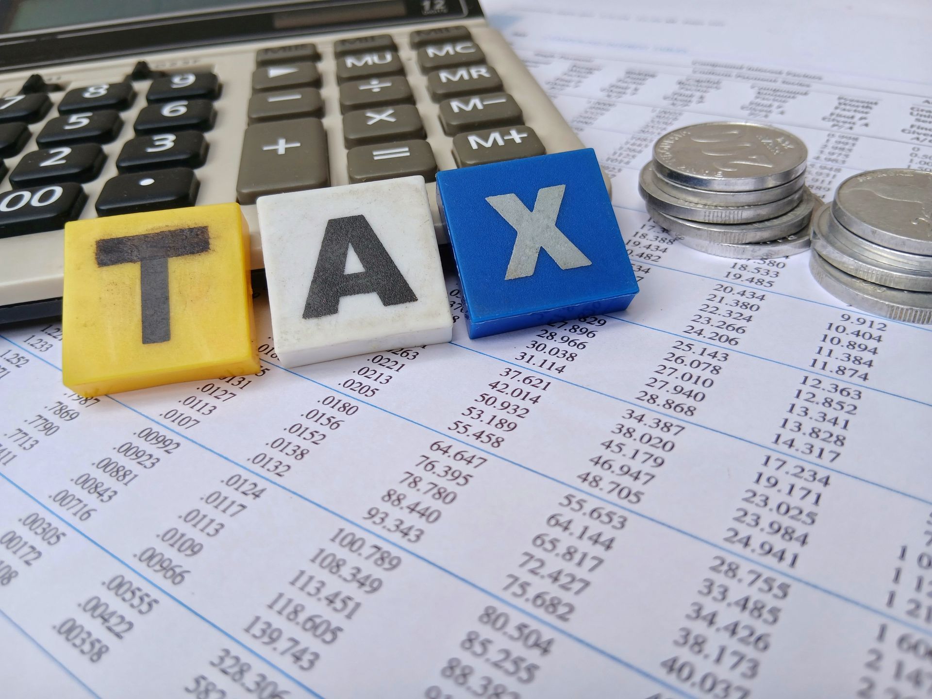 Tax calculator with stacked coins and paperwork on a desk