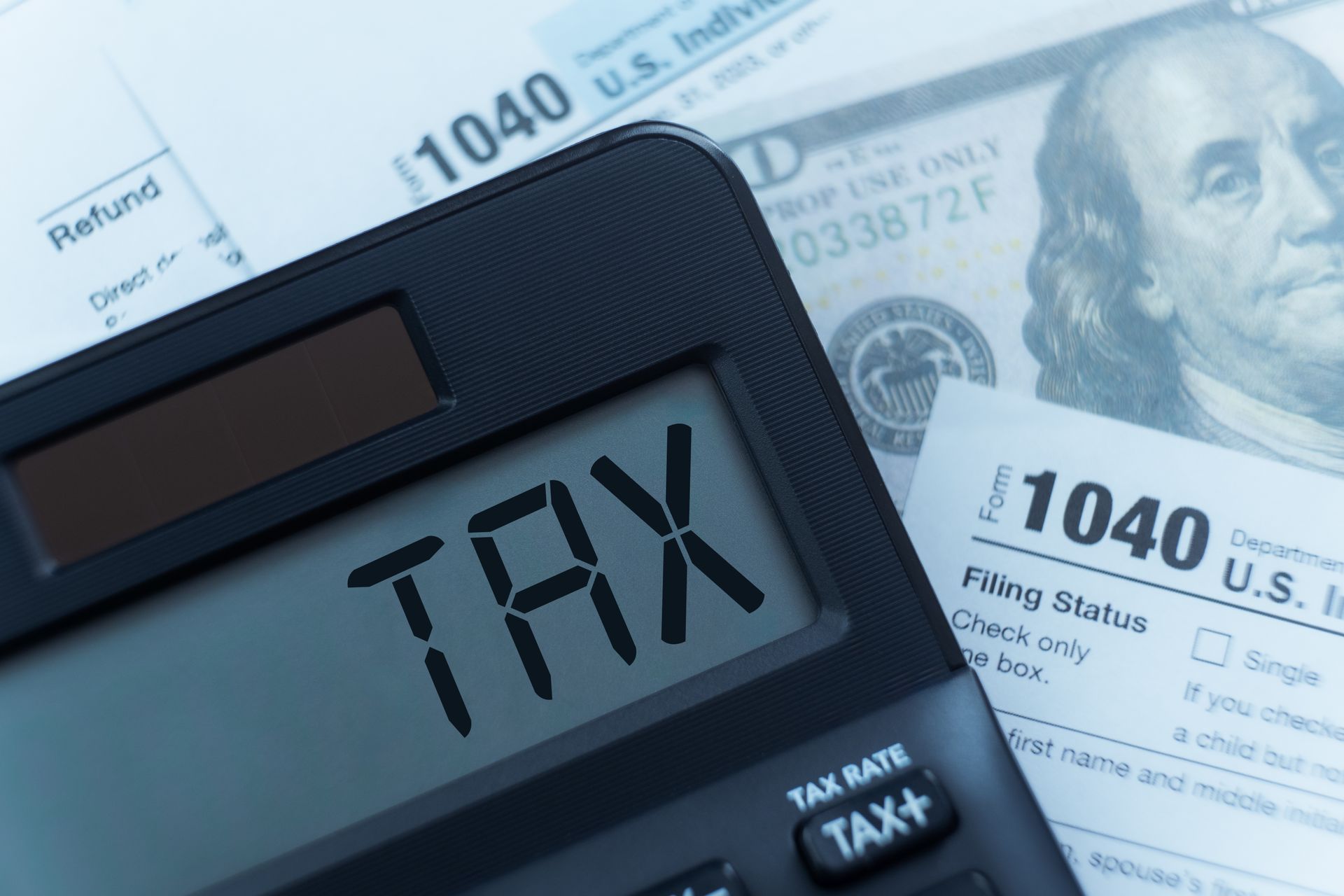 Tax calculator on U.S. 1040 tax forms with a portrait of Benjamin Franklin visible on a bill