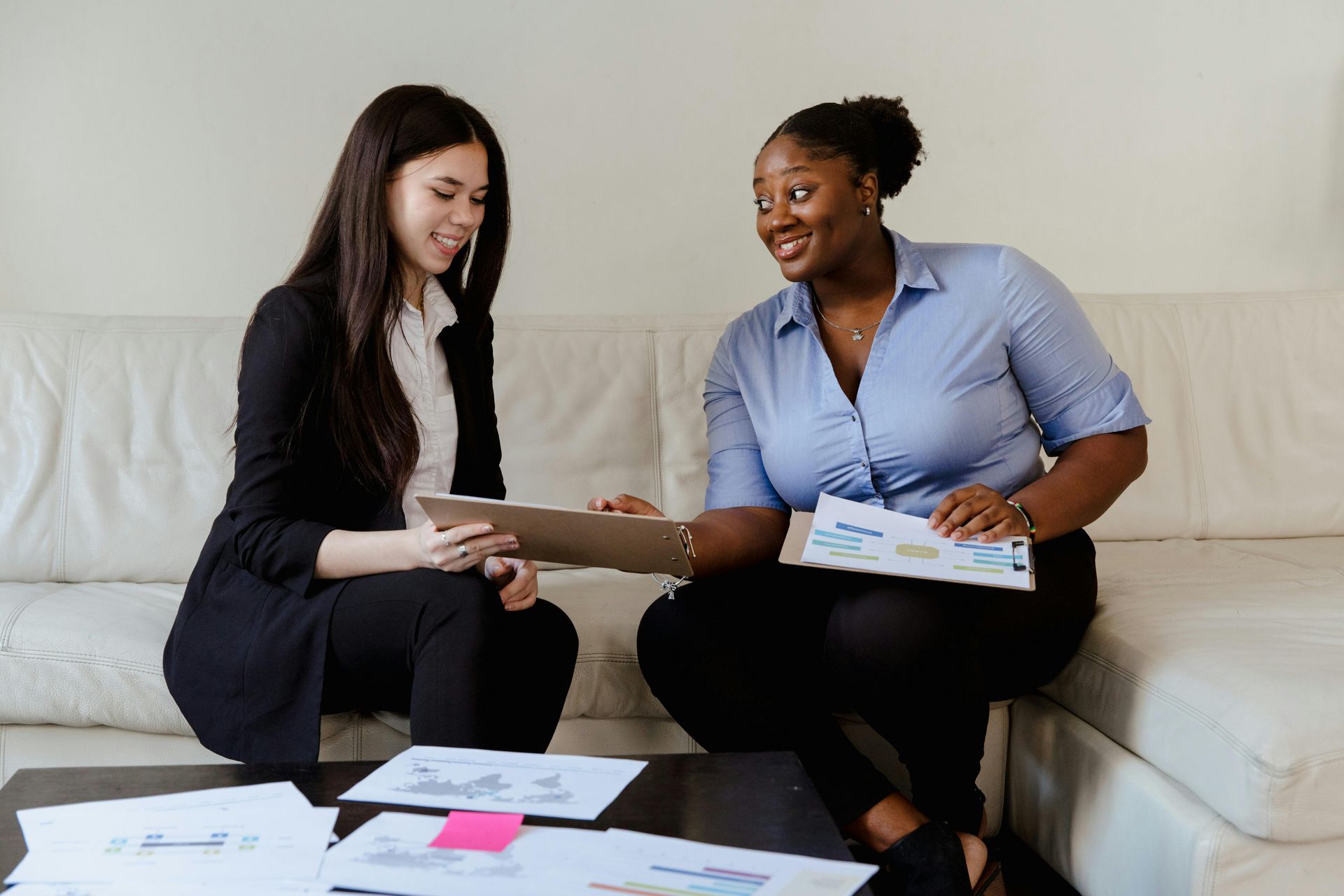 Two people sitting on the floor reviewing bills and paperwork beside a couch