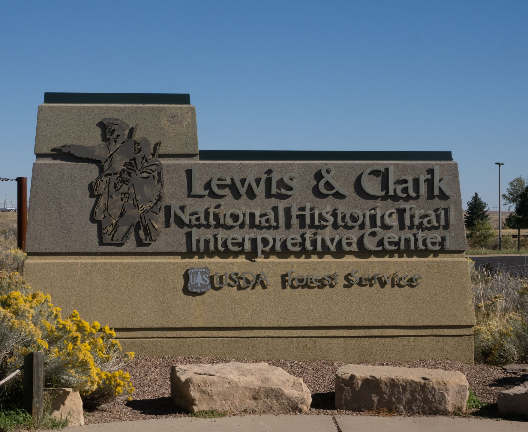 The stone sign for the Lewis & Clark National Historic Trail Interpretive Center in a landscape setting.