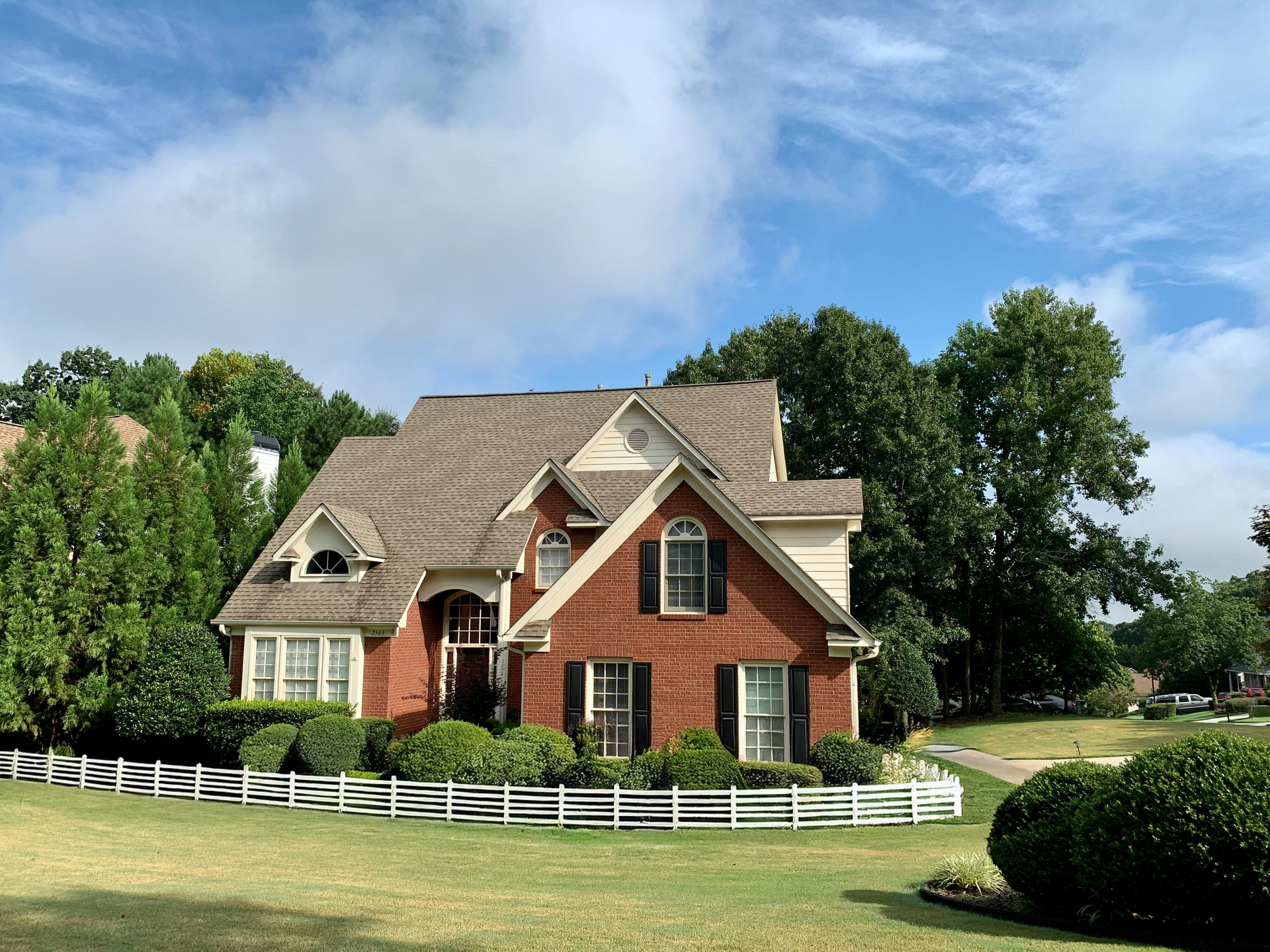 A large brick house with a white fence in front of it