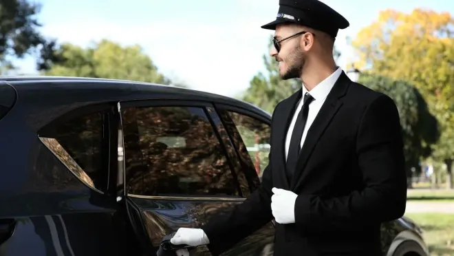 A man in a suit and tie is opening the door of a car.