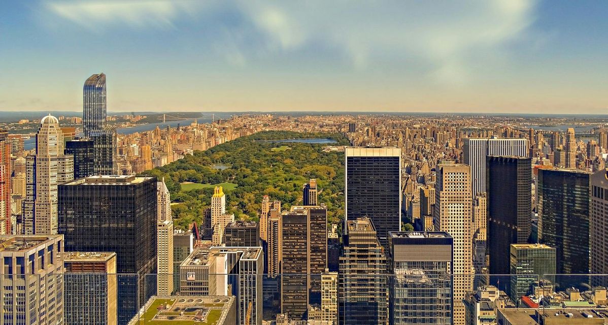 An aerial view of a city with a park in the background.
