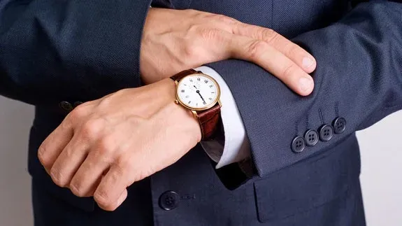 A man in a suit is looking at his watch.