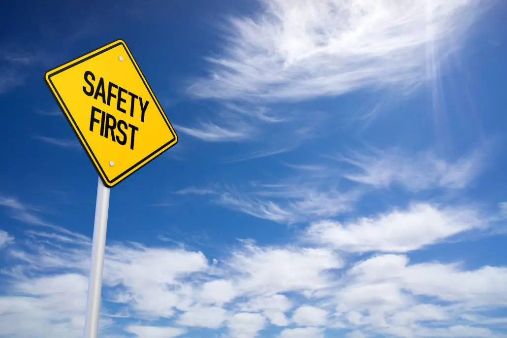 A safety first sign is against a blue sky with clouds.