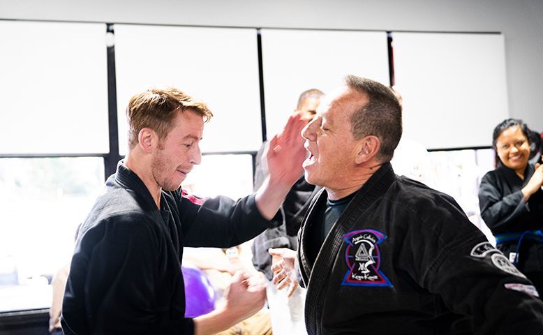 A man is giving another man a high five in a karate class.