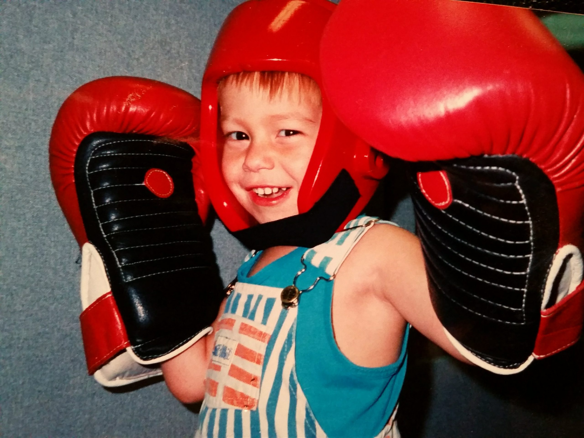 A young boy wearing boxing gloves and a helmet