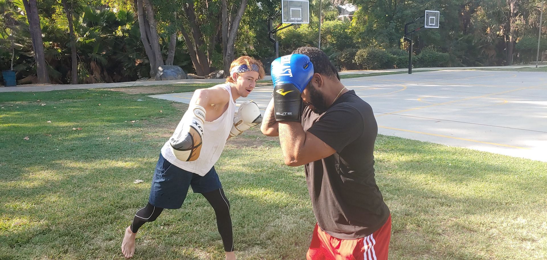 Two people boxing outdoors, one throwing a punch.