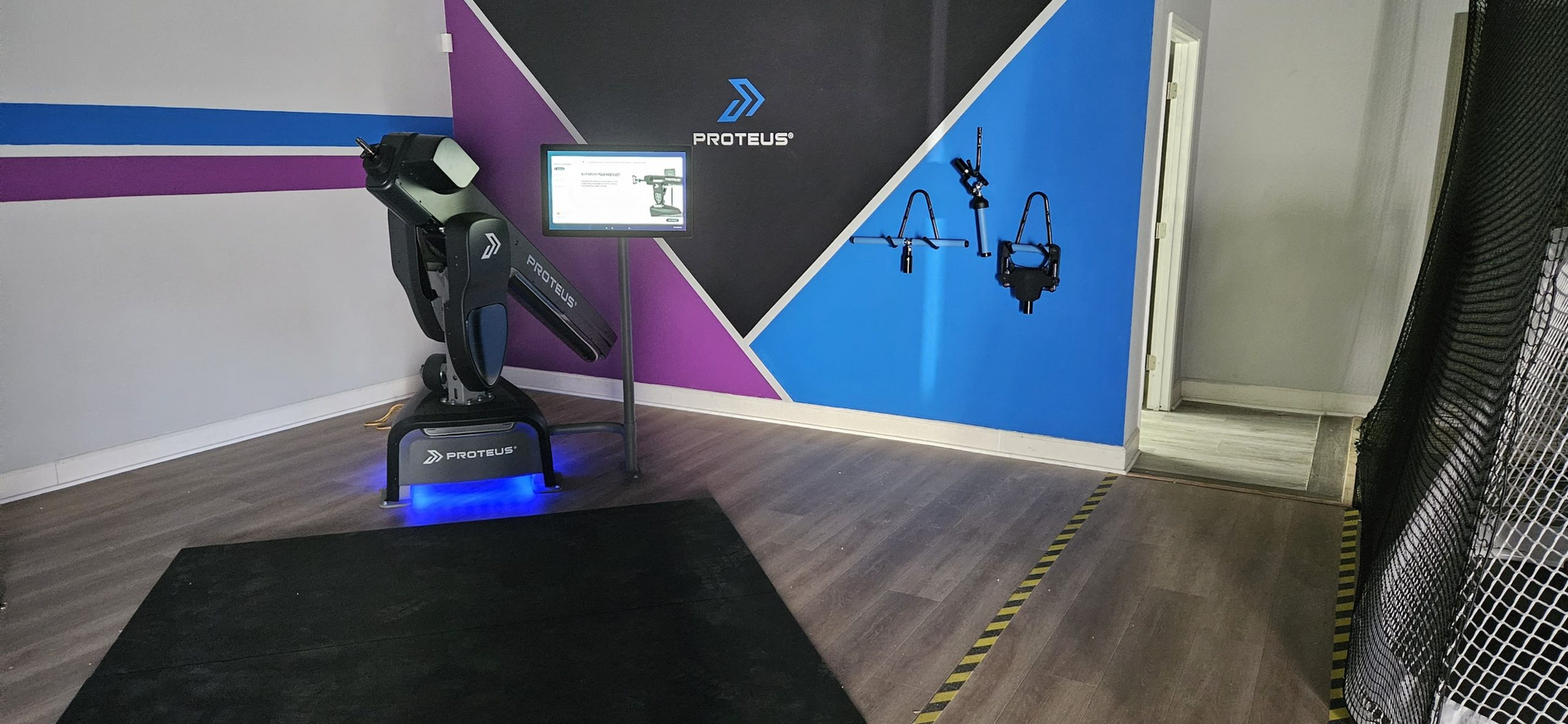 A room with a robot arm and a tv on the wall.