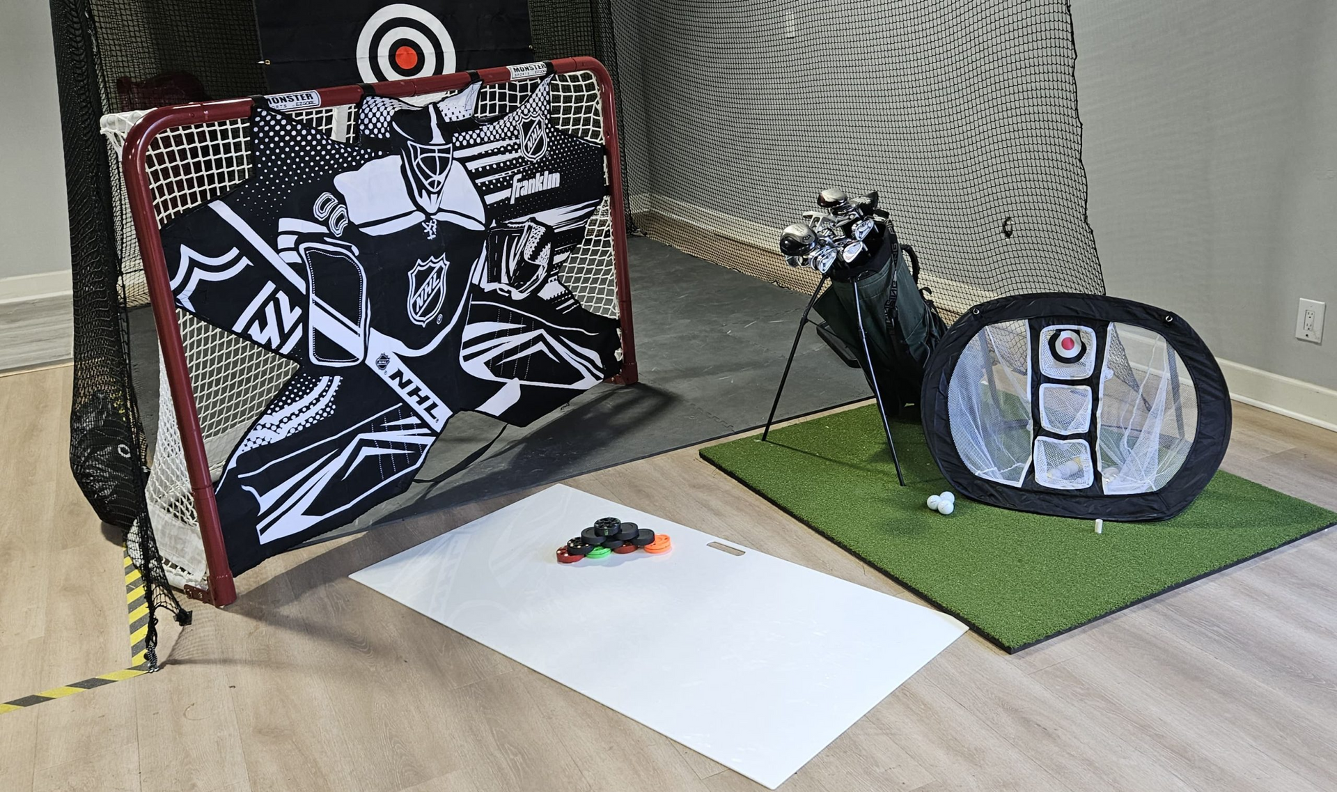 A hockey net is sitting on top of a wooden floor next to a golf bag.