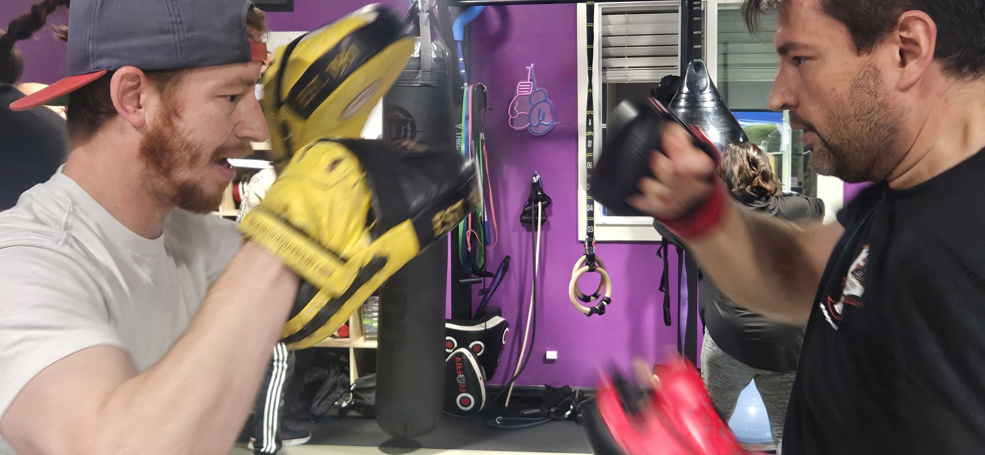 Two men are boxing in a gym while wearing boxing gloves.